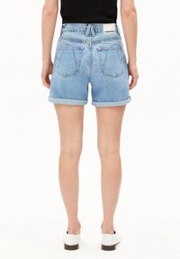 Helle Denim-Shorts mit umgeschlagenem Saum, hohe Taille, zwei Gesäßtaschen und einem Logo-Etikett am Bund. Glatte Textur.