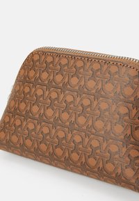 Custodia marrone con zip caratterizzata da un design testurizzato con pattern intrecciati di un marrone più scuro. Realizzata in materiale resistente, con una zip liscia.