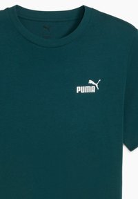 Tyrkysové bavlněné tričko s kulatým výstřihem a krátkými rukávy, s bílým logem Puma umístěným na levé části hrudníku.