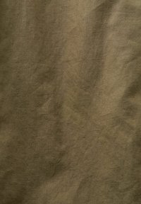 Oliven grønn teksturert stoff med en litt rynket overflate, som viser et naturlig materialeutseende og subtil glans.