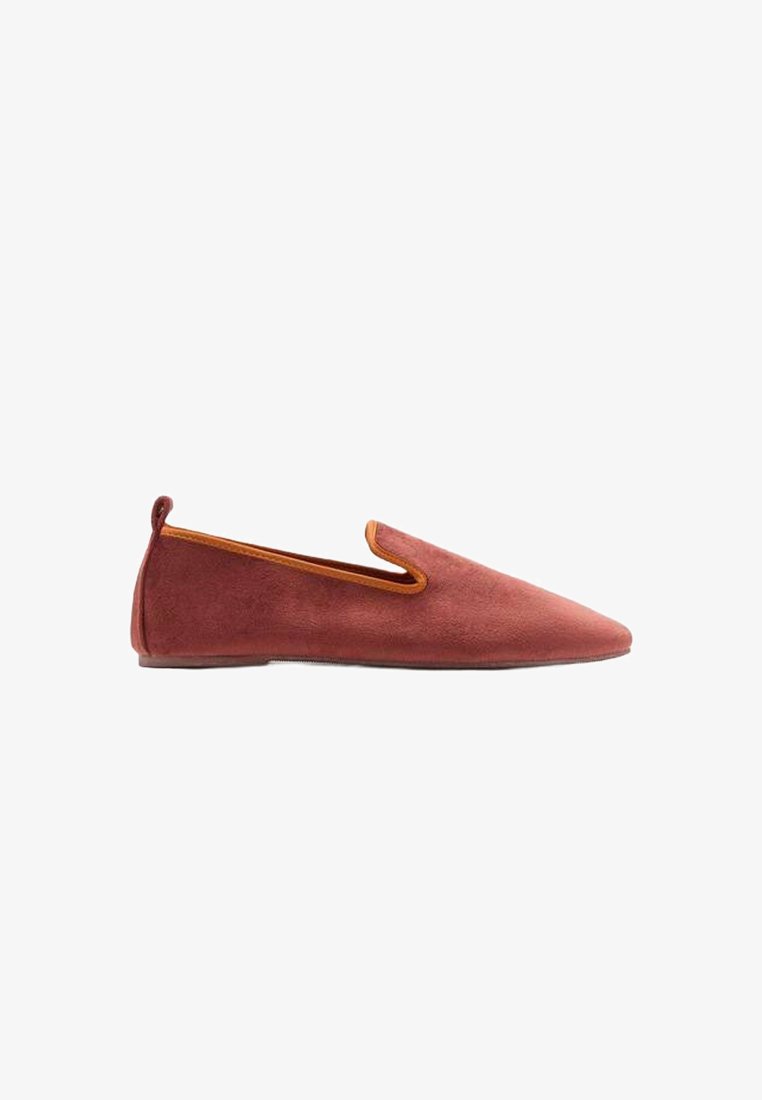 Scarpa slip-on in suede rosso con punta affusolata, che presenta un'accenno arancione lungo l'apertura e una suola piatta. Trama liscia, design minimale.
