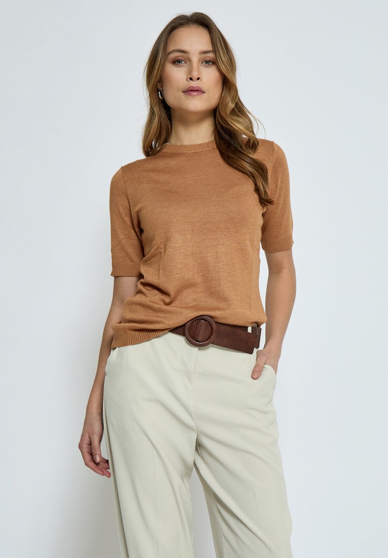 Hnědý pletený svetr s krátkým rukávem a žebrovaným výstřihem, doplněný o světle béžové kalhoty a tmavě hnědý pásek se zaoblenou sponou.