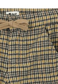Pantalones de lana con un patrón de cuadro en amarillo, marrón y negro, con un cinturón beige atado y una pequeña etiqueta de la marca visible en la cinturilla.