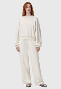 Conjunto de loungewear color crema que incluye un sudadera de corte relajado con puños acanalados y pantalones de pierna ancha de alta cintura en una tela suave.