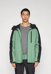 Πράσινο και μαύρο μπουφάν με κουκούλα, με φερμουάρ μπροστά, πλαϊνές τσέπες και σχεδιασμό αντίθετων �μανικιών. Λεία υφή, casual εφαρμογή.