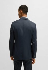 Giacca di suit a righe blu scuro con colletto rever, chiusura frontale a due bottoni e dettagli di bottoni ai polsini.