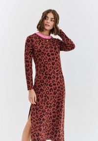 Dlouhé hnědé šaty s černým leopardím potiskem, se růžovým límečkem a bočním rozparkem. Vyrobené z měkké látky s dlouhými rukávy.
