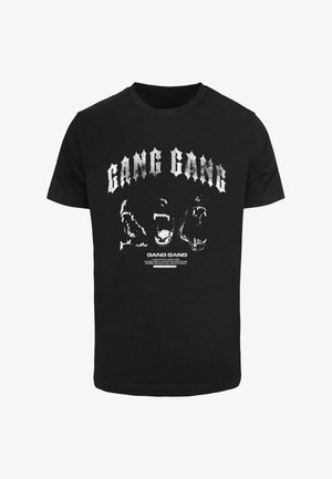 Must musta t-särk, millel on julged valged graafilised tekstid "GANG GANG" ning loomapeade kujutised. Lühikesed varrukad ja klassikaline ümar kaelus.