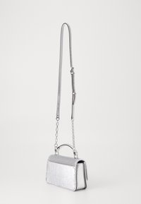 Srebrna metaliczna torebka o usztywnionej konstrukcji, z teksturowaną przednią częścią, odpinanym łańcuszkowym paskiem i małym górnym uchwytem.