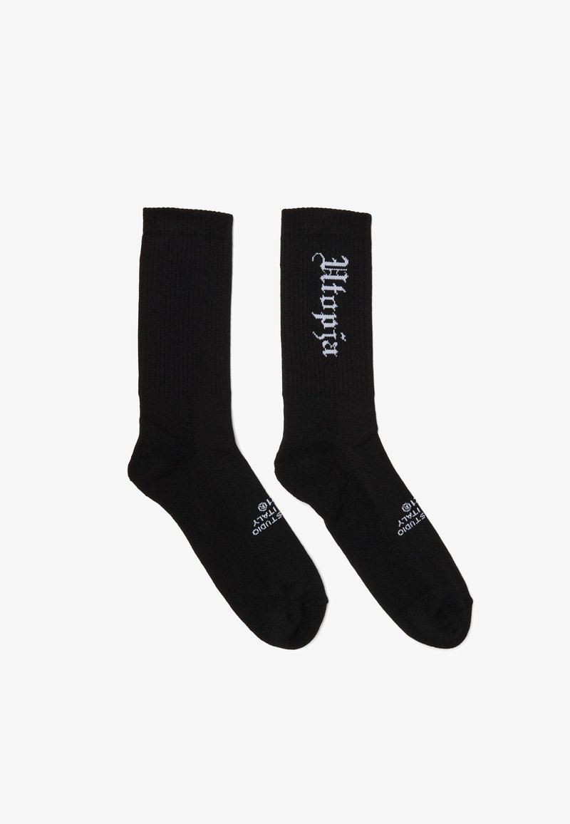 Par de calcetines negros hasta el tobillo con textura acanalada, texto blanco "Wacko Maria" en la zona de la pantorrilla y texto pequeño blanco cerca de los dedos.