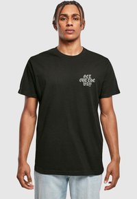 Sort bomulds T-shirt med korte ærmer, der har hvid tekst på venstre brystområde, som siger "GET OUT THE WAY." Klassisk pasform.