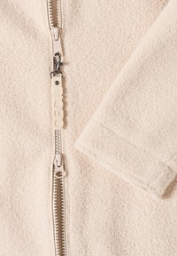 Giacca in fleece beige con una trama liscia, dotata di una zip centrale e di un tirante della zip con il marchio "CECIL" inciso.