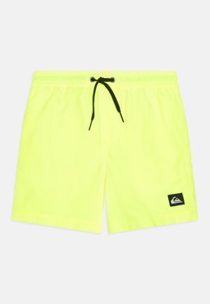 Neon gele zwembroek gemaakt van lichtgewicht materiaal met een zwarte trekkoord en een logo-patch aan de linkerkant.