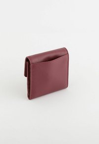 Petit portefeuille bordeaux avec une surface texturée, de forme rectangulaire, à compartiment unique et aux coins arrondis. Design simple sans éléments métalliques apparents.