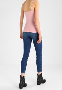 Rosa slim-fit linne, blå skinny jeans och svarta ankelboots med nitar. Slät tyg, figursydd design och avslappnad stil.