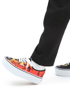 Barevné vzorované tenisky Vans mají vysoce kontrastní tie-dye design v oranžové, žluté a černé barvě, bílé tkaničky a platformové podrážky.