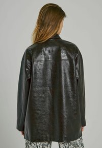 Must have faux nahkjack, millel on tekstureeritud krokodillimuster, oversized sobivus ja tagaküljel yoke detail. Stiliseeritud madusid sarnanevate pükstega.