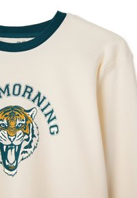 Sudadera crema con cuello verde oscuro que presenta la cabeza de un tigre rugiendo y la palabra "MORNING" encima en letras verdes.