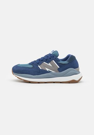 Blue athletic shoe featuring a mix of suede and mesh materials, with a light blue and gray design, a white midsole, and a brown outsole.