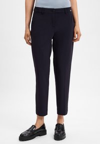 Marineblauwe op maat gemaakte broeken van een gladde stof, slim fit, met zijzakken en een knoopsluiting. Kenmerken zijn de verkorte enkels en een minimaal merklogo.