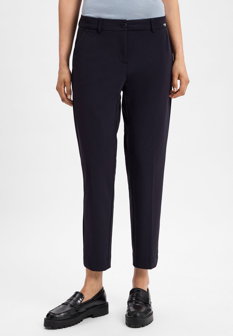 Marineblauwe op maat gemaakte broeken van een gladde stof, slim fit, met zijzakken en een knoopsluiting. Kenmerken zijn de verkorte enkels en een minimaal merklogo.