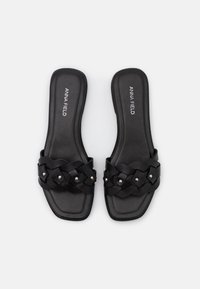 Svarta platta sandaler har en vävd remdesign med silverfärgade nitar. Sulan är slät och rektangulär för extra komfort.
