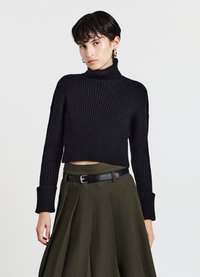 Maglione nero a costine con colletto alto e maniche lunghe, di lunghezza cropped e con polsini larghi, abbinato a una gonna verde oliva a vita alta e una cintura nera.