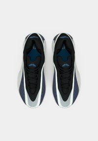 Melni un tumši zilas sporta kurpes ar elegantu dizainu, kas izceļ teksturētu augšdaļu, baltas detaļas un zilu oderi, demonstrējot zemu profilu.