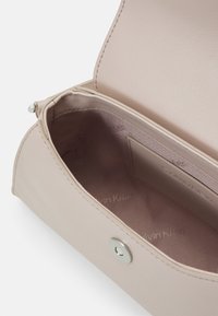 Jasnoróżowy skórzany portfel o gładkiej fakturze, z magnetycznym zapięciem i wnętrzem tłoczonym nazwą marki, wyposażony w jedno miejsce na kartę.