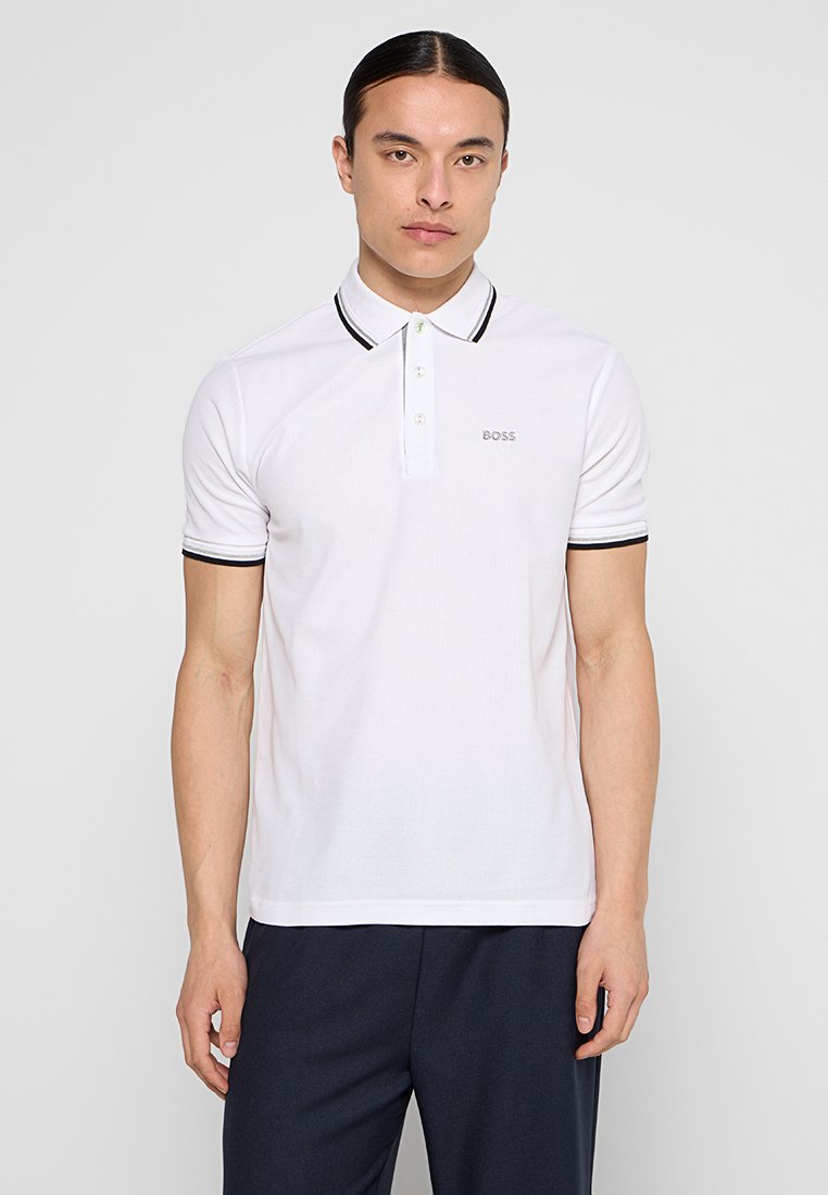 Camisa polo blanca hecha de tejido texturizado, con un cuello acanalado con acentos negros y un pequeño logotipo en el pecho. Manga corta.