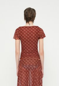 Red plaid fitted top with short sleeves, made from a sheer material. Features a square neckline and a layered hem design.