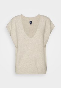 Pull tricoté beige avec col en V, manches courtes et ourlet côtelé. Texture douce avec un motif subtil partout. Étiquette de marque visible.