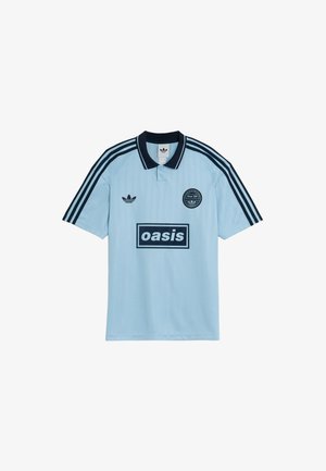 Vaaleansininen polo-paita mustilla yksityiskohdilla, jossa on kaksinappinen kaulus, kolme mustaa raitaa hihoissa ja "oasis"-logo edessä.