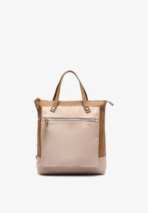 Tweekleurige beige leren totebag met dubbele handvatten en een voorvak met ritssluiting tegen een witte achtergrond.