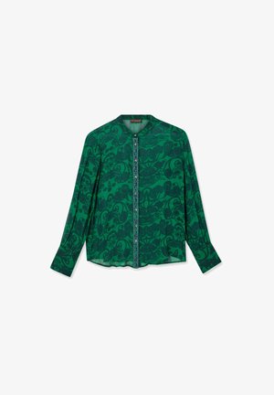 Roheline pluus pikkade varrukatega, millel on tumesinine lillemuster. Ümar kaelus ja nööbiga sulgemine ees. Kerge kangas.