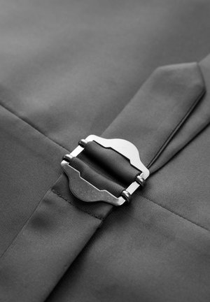 Schwarzer Stoff mit einer silbernen Metallschnalle, glatte Textur und klare Linien mit einer Nahtdetail, das ein elegantes und funktionales Design einfängt.