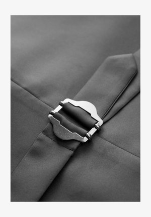 Black textile featuring a silver metal buckle, smooth texture, and clean lines with a seam detail, capturing a sleek and functional design.