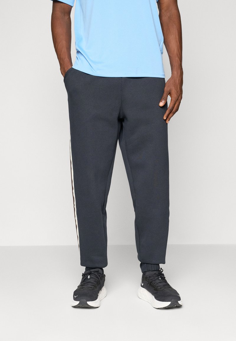 Donkergrijze sweatpants met een taps toelopende pasvorm, voorzien van zijstrepen in het wit en bruin. Gemaakt van zacht materiaal, ontworpen voor comfort.