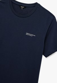 Camiseta de manga corta en color azul marino, fabricada en un tejido suave, con cuello redondo. En el pecho, un gráfico de texto que dice: "CARRERAS MATUTINAS Y SOLES QUE SALEN, CORRE COMO SI FUERA UN DÍA DE CARRERA."
