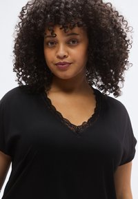 Black V-neck t-shirt made of soft fabric, featuring lace trim along the neckline. Short sleeves and relaxed fit for comfort.