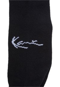 Svart socka av ribbad struktur, med en vit logotypdesign. Tå- och hälområdena är förstärkta för ökad hållbarhet.