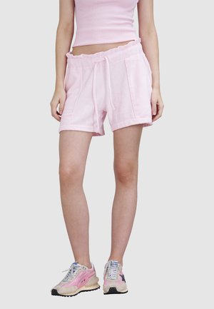 Shorts en coton rose avec une taille à cordon de serrage, deux poches latérales et des ourlets retroussés. Assortis à des chaussures de sport rose et gris.