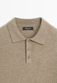 Beżowa dzianinowa koszulka polo o fakturowanym wykończeniu, z trzema guzikami i ściągaczem u kołnierza. Metka mówi "Massimo Dutti."