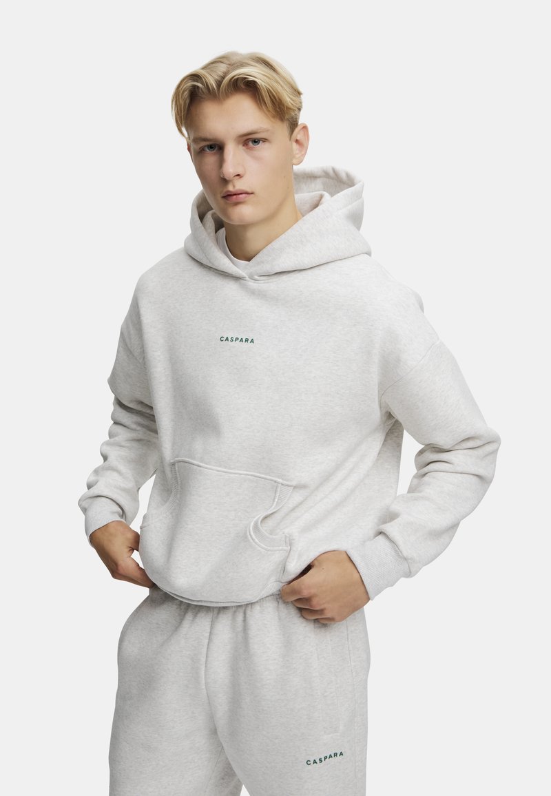 Grå hoodie lavet af en bomuldsblanding, med en frontlomme og ribbede manchetter. Mærket "Caspara" er trykt i grønt på brystet.