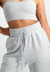 Grijze geribbelde crop top met dunne bandjes, gecombineerd met lichtgrijze joggingbroeken met een elastische tailleband en een trekkoord.