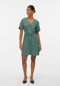 Abito verde con bottoni, scollatura a V, maniche corte e vita legata. Tessuto liscio, lunghezza al ginocchio, design minimalista.