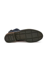 Semelle en caoutchouc noir avec un motif de grip, présentant une forme arrondie et une finition texturée. Tige en cuir bleu foncé avec une sangle élastique.