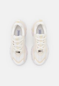 Sneaker bianche e crema con una tomaia in rete testurizzata, lacci robusti e una suola spessa e scanalata. Logo sulla linguetta e sul lato.