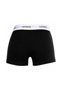 Čierne bavlnené boxerky s bielym elastickým pásom s brandovaním "LACOSTE". Hladká textúra, klasický strih a žiadne ďalšie ozdoby.