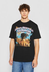 Black cotton t-shirt featuring a large graphic of a person with butterflies, text "DAYS BEFORE SUMMER," and a relaxed fit.